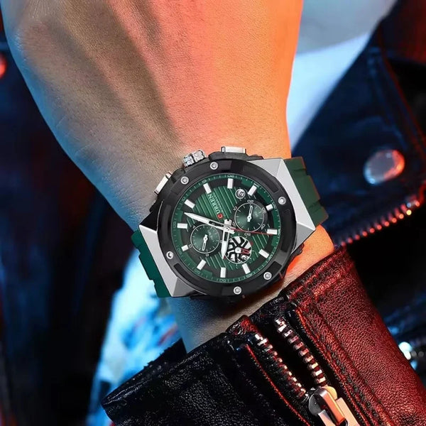 Close-up of a wrist wearing a green and silver watch with a red jacket sleeve.