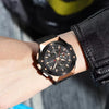 Black wristwatch with rose gold accents on a person's wrist.