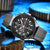 Black and gray wristwatch with detailed face on a blue mechanical gear background